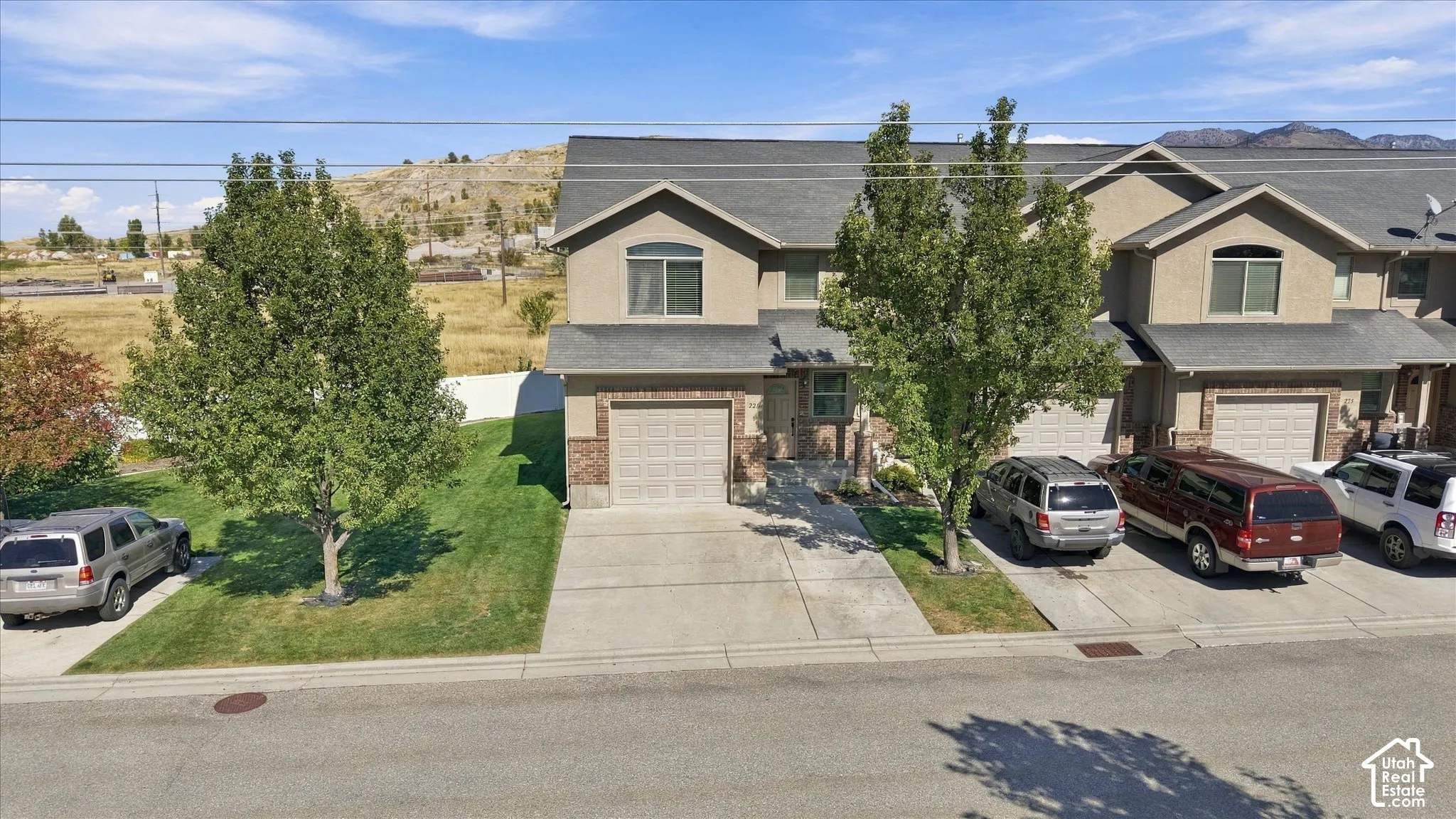 Townhome exterior featuring a stucco and brick facade, a two-car garage, and established front landscaping