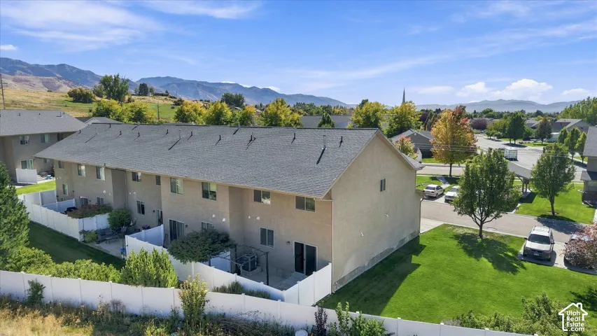 Townhome exterior featuring tan stucco siding, a dark shingle roof, and private fenced patios