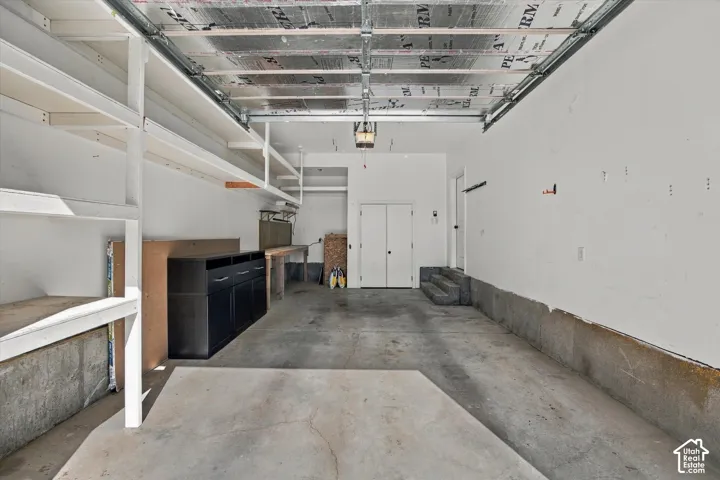 Built-in shelving, concrete flooring, dual entry doors, built-in workbench, and overhead lighting