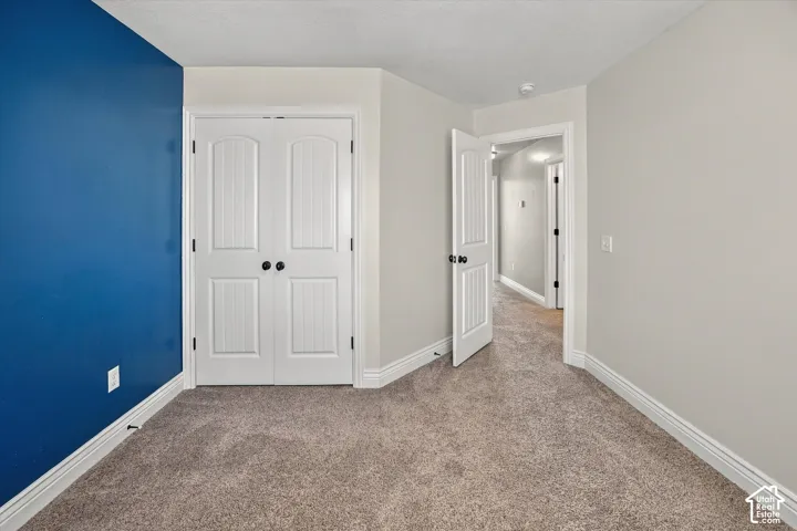 Plush carpeting, interior paneled doors, white trim, and a neutral wall color complement a vibrant accent wall