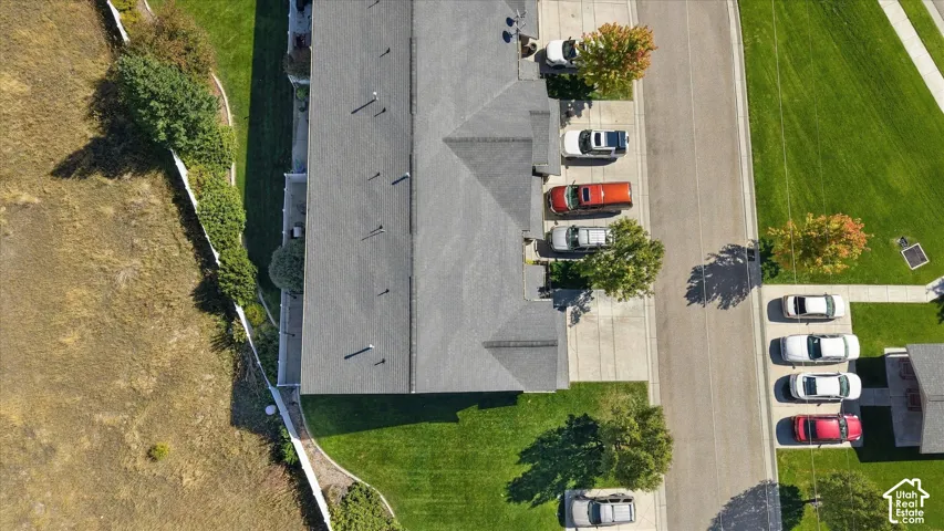 Pitched roofline with multiple vents, dedicated driveway, concrete walkways, and green lawn areas