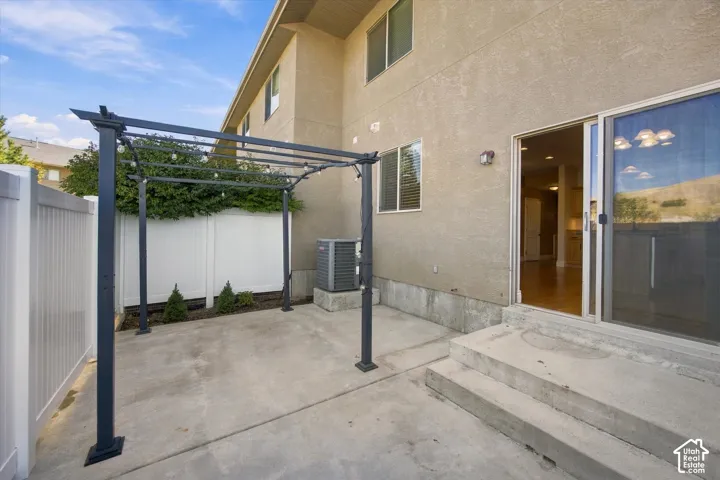 Patio with a pergola, concrete steps, sliding glass door, and a white privacy fence