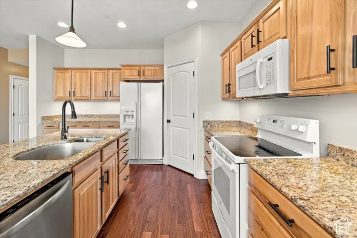 Kitchen featuring wood-finish cabinetry, granite countertops, stainless steel sink with a gooseneck faucet, and wood-look flooring