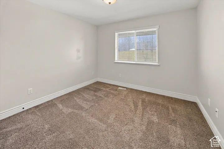 Neutral wall color, wall-to-wall carpeting, window with blinds, white trim, and a ceiling-mounted light fixture