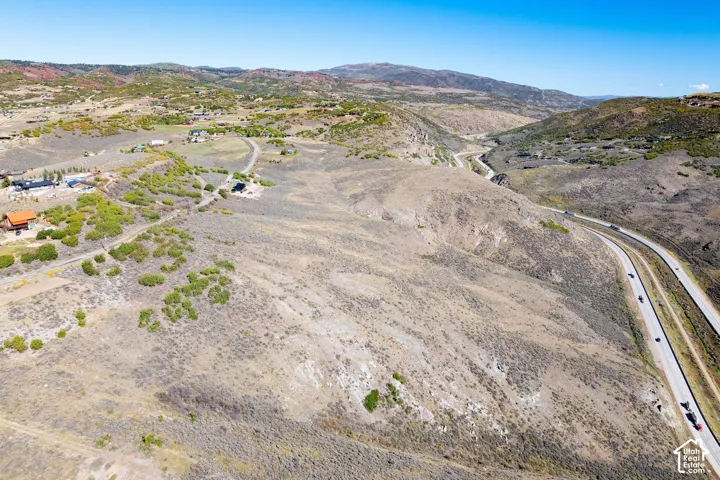 Expansive undeveloped terrain featuring a prominent roadway and distant residential structures