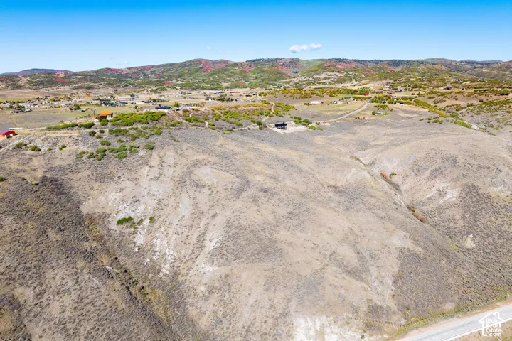 Expansive undeveloped land featuring rolling hills and distant residential structures