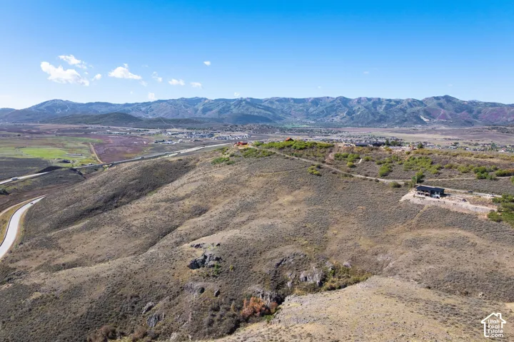 Additional contentThe photo is an aerial/landscape view showing terrain, vegetation, a winding road, and distant mountains
