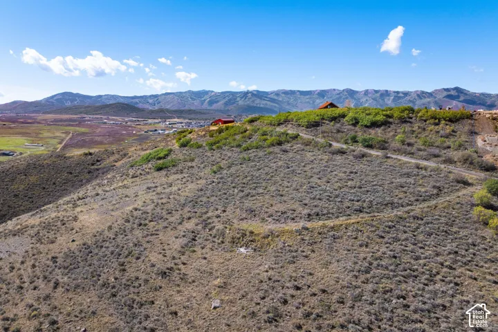 Expansive hillside property featuring natural vegetation, a dirt path, and distant mountain ranges