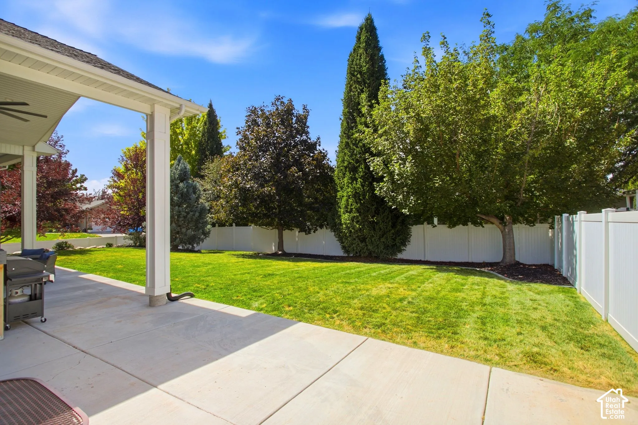 Covered patio with mature trees and full vinyl fence