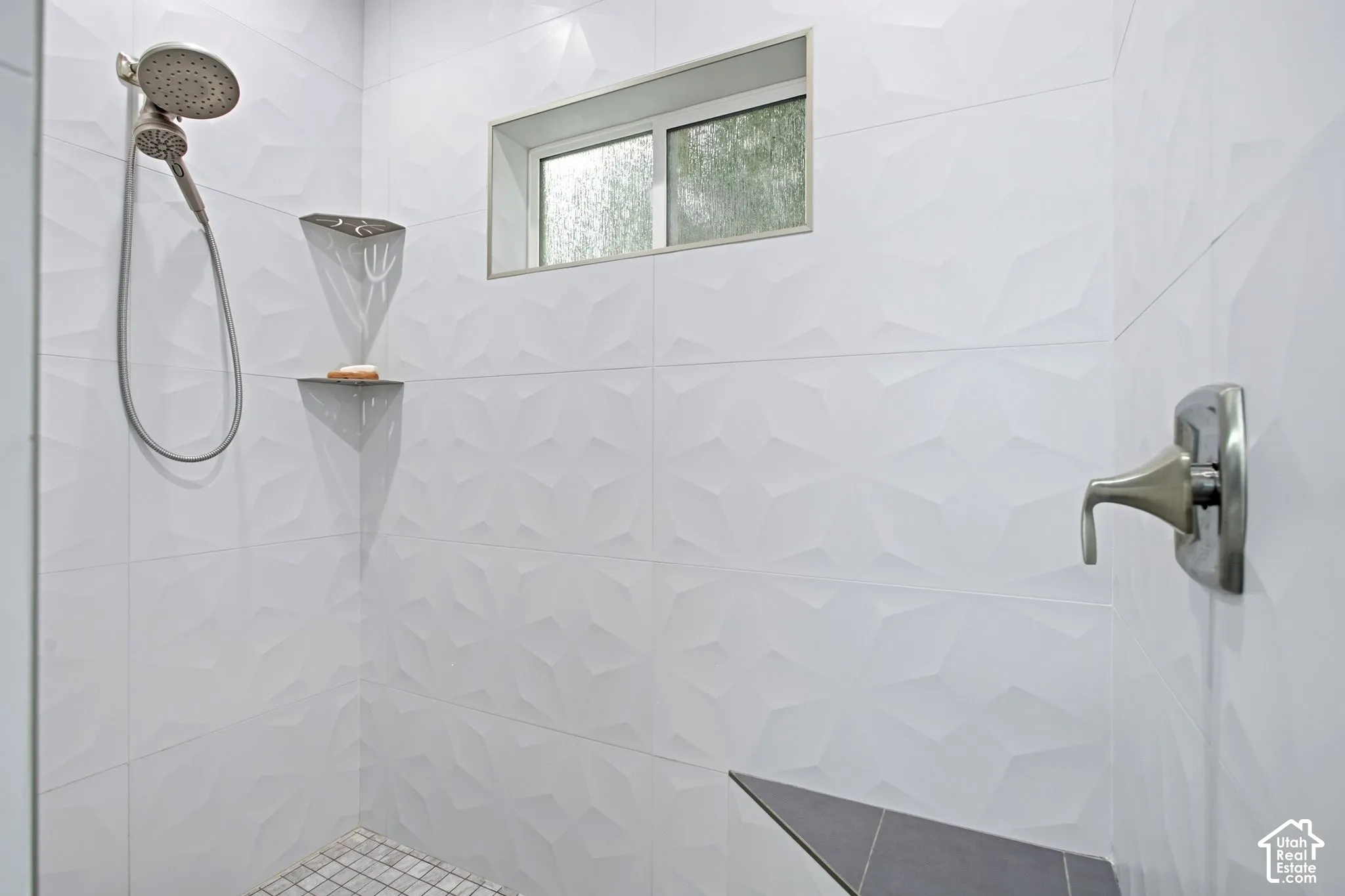 Primary en-suite shower with textured white tile walls, a built-in bench and a rain showerhead