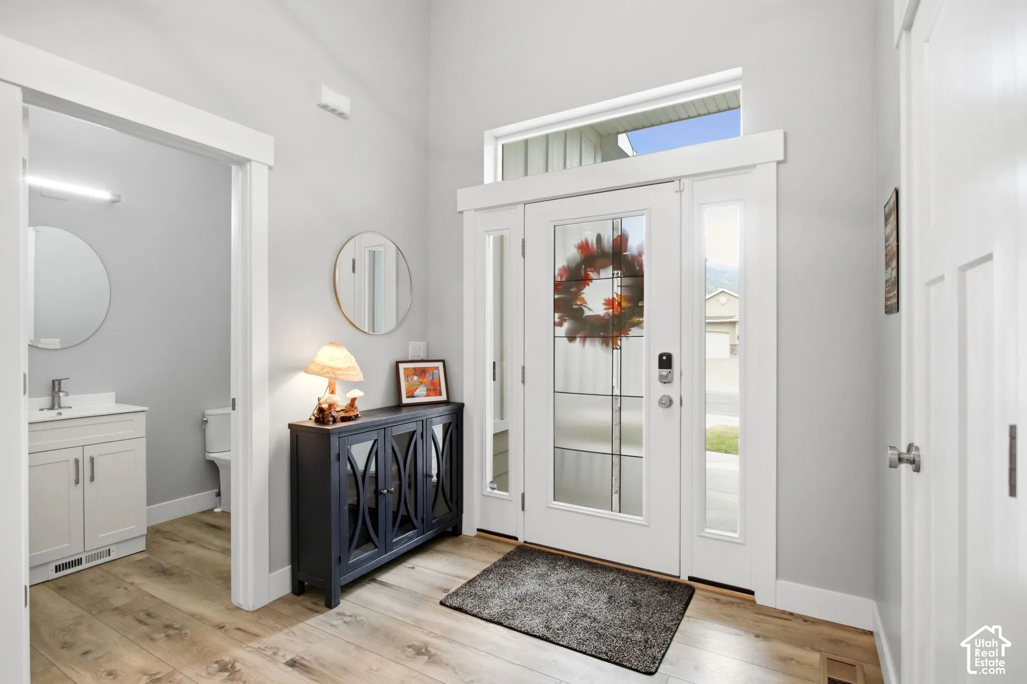 Entryway with wood flooring and 10 Ft ceiling-view of guest bathroom