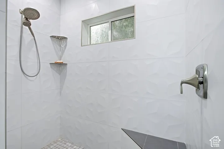 Primary en-suite shower with textured white tile walls, a built-in bench and a rain showerhead