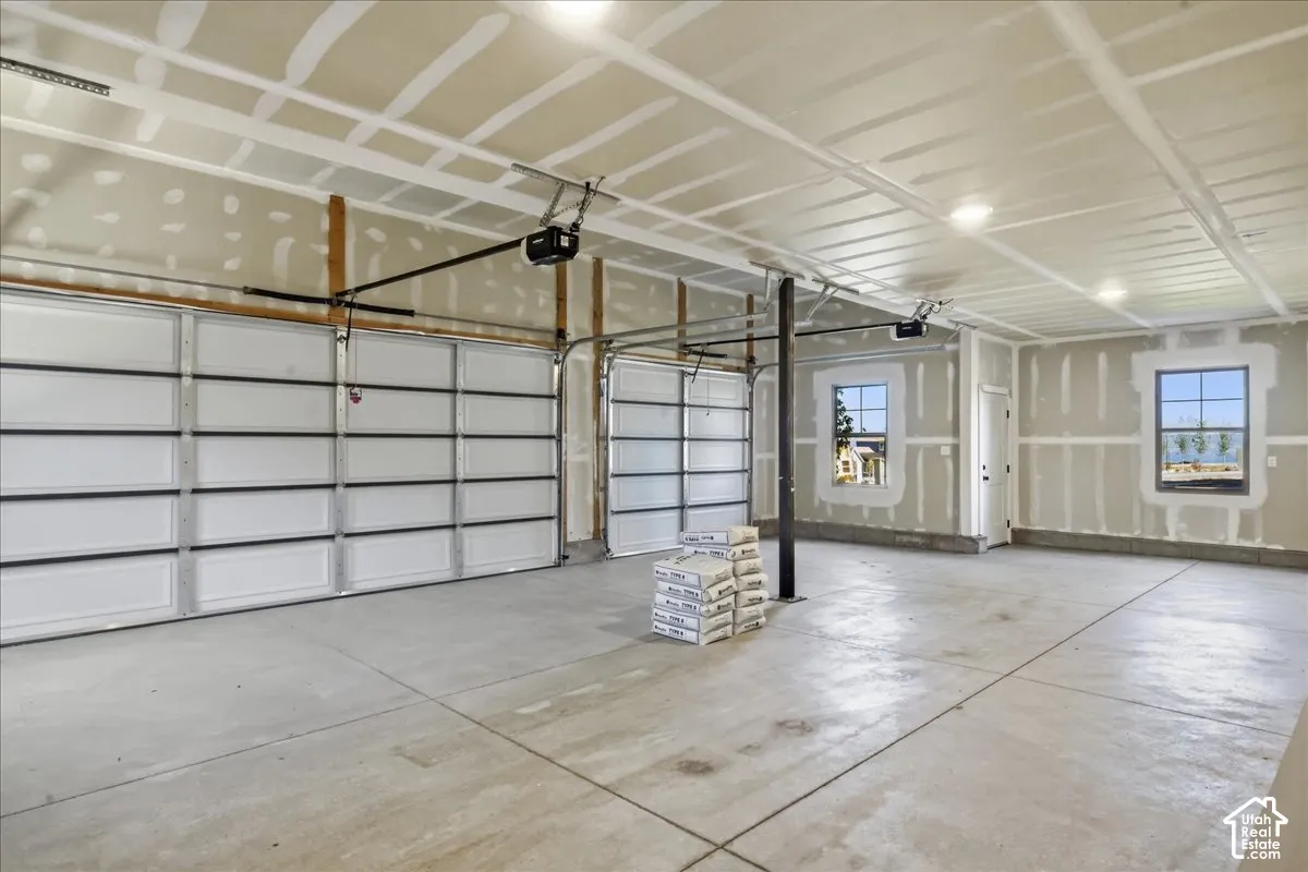 Concrete flooring with two overhead garage doors, two windows, and recessed lighting