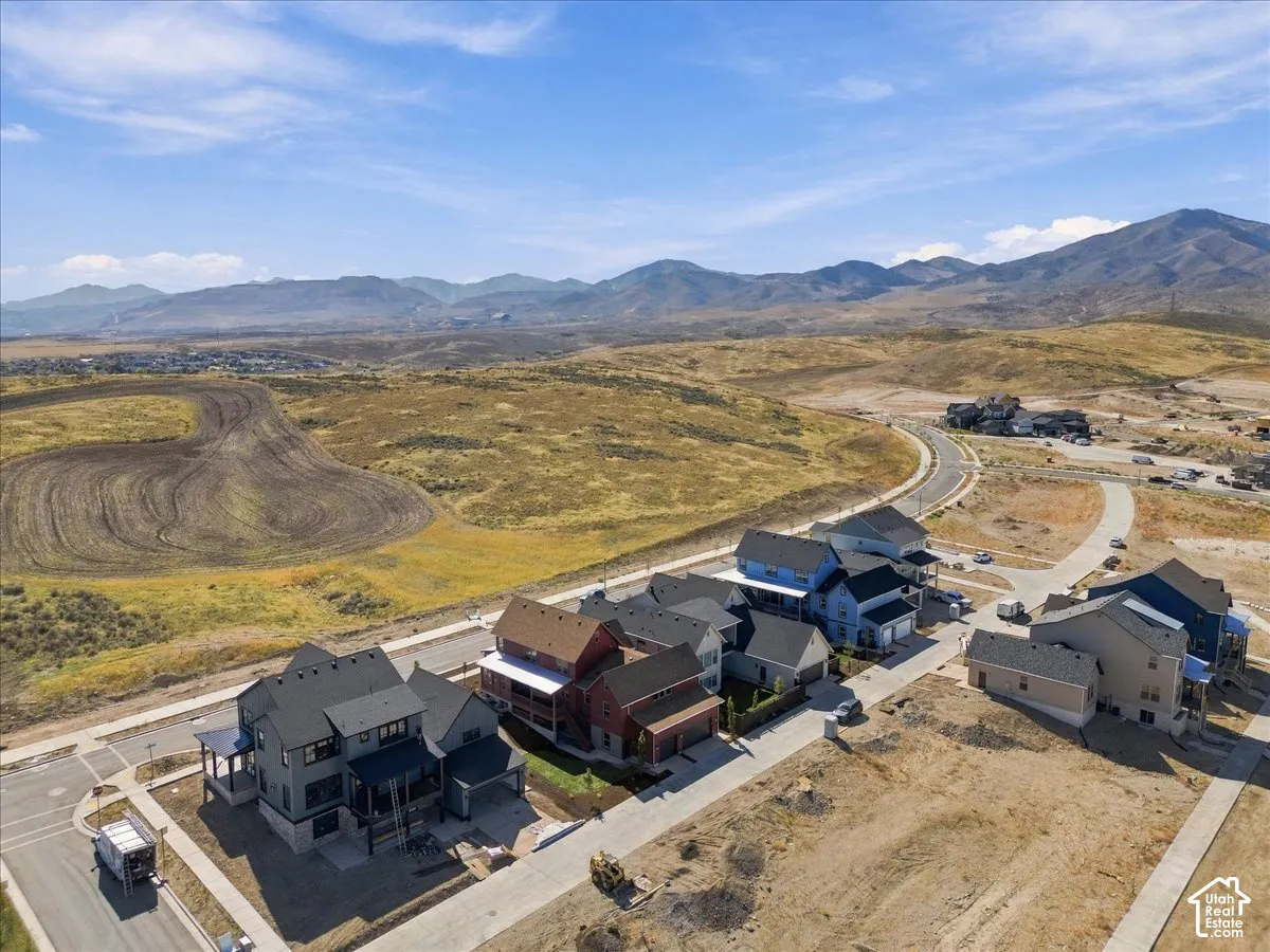 Mountain backdrop, paved roads, organized neighborhood layout, varied architectural styles, and undeveloped land