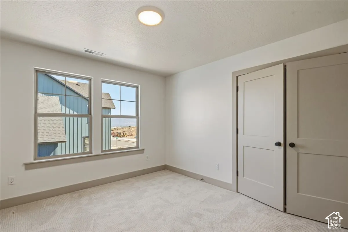 Upstairs guest bedroom 2 Recessed ceiling light, dual pane windows, light-toned carpeting, white walls, and paneled closet doors with black hardware