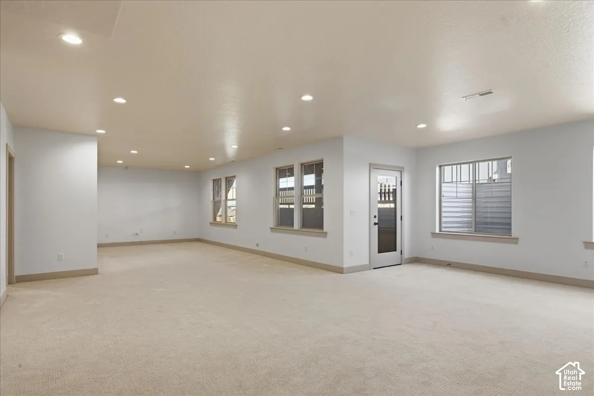 Basemen tExpansive interior space with recessed lighting, light-colored carpeting, multiple windows, and a glass-paneled door