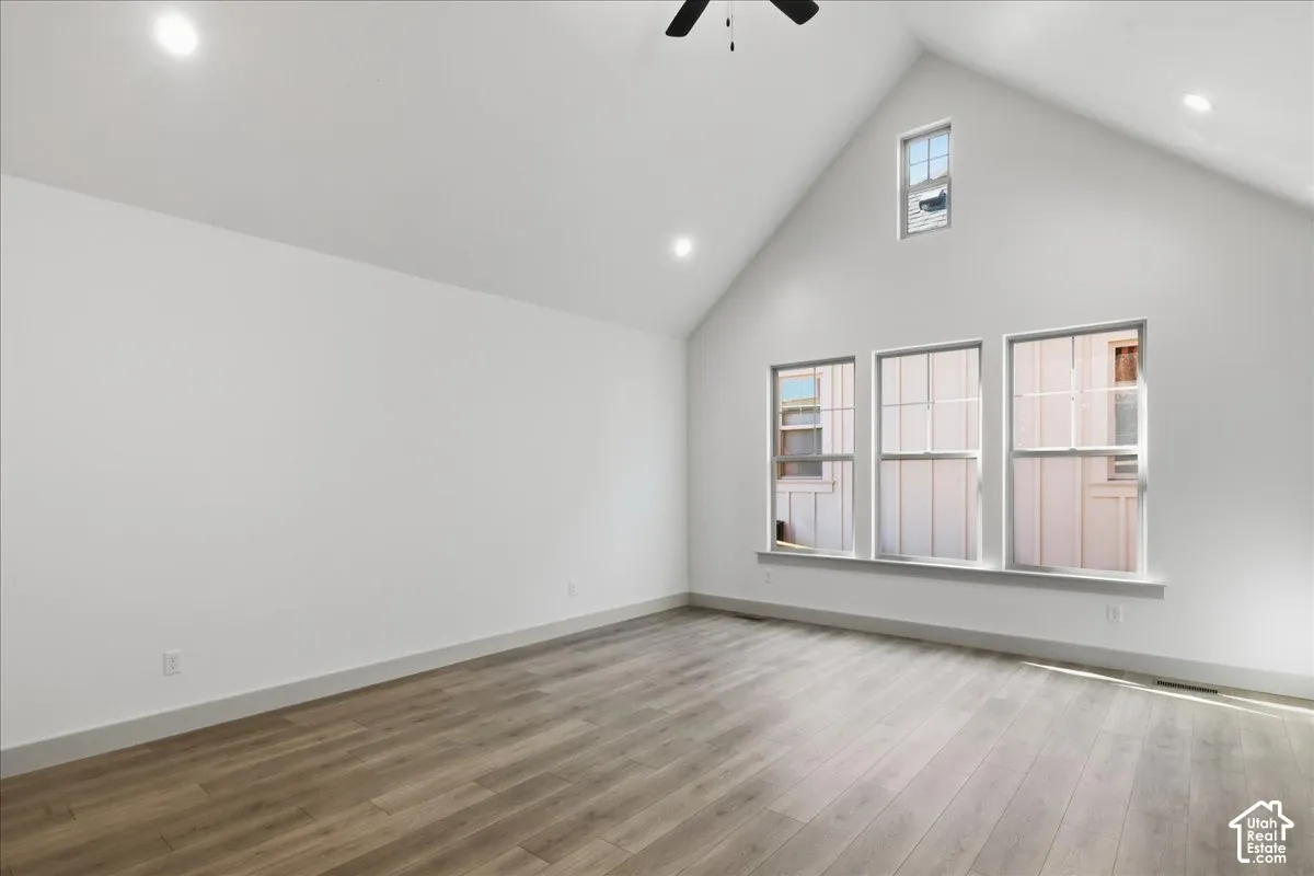 Main Floor Primary Bedroom Vaulted ceiling, wood-finish flooring, recessed lighting, ceiling fan, and multiple windows