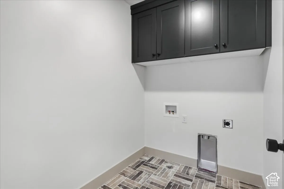 Dark-toned cabinetry, tile flooring with a herringbone pattern, and a utility hookup area