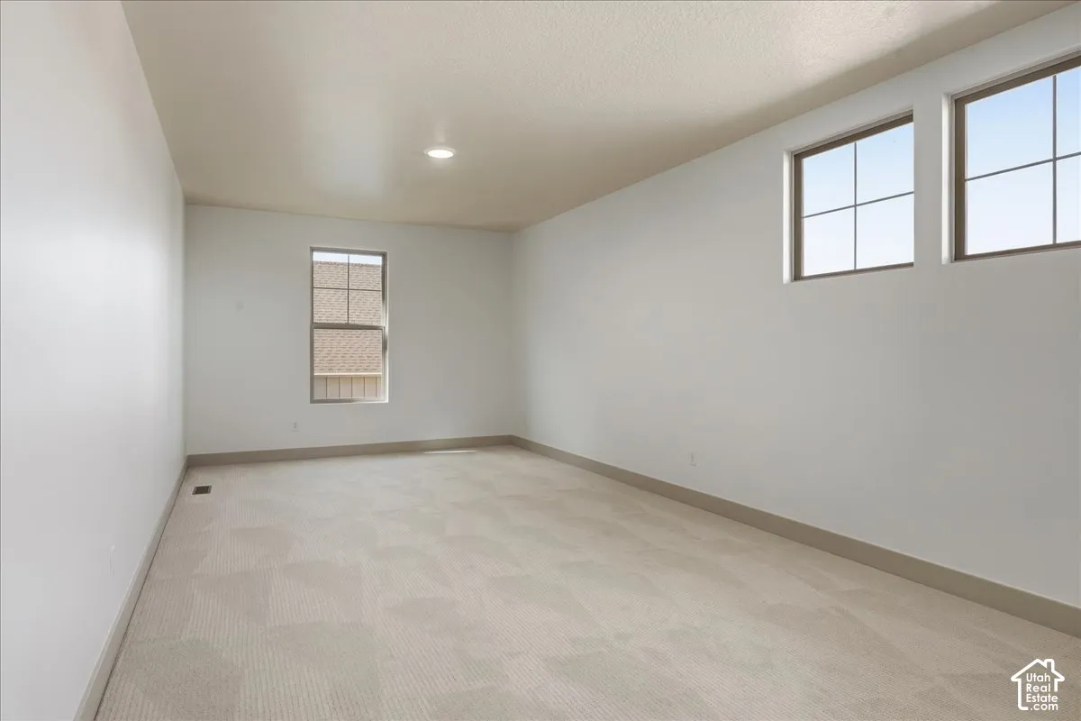 Neutral wall paint, patterned carpet flooring, recessed ceiling lighting, and multiple windows