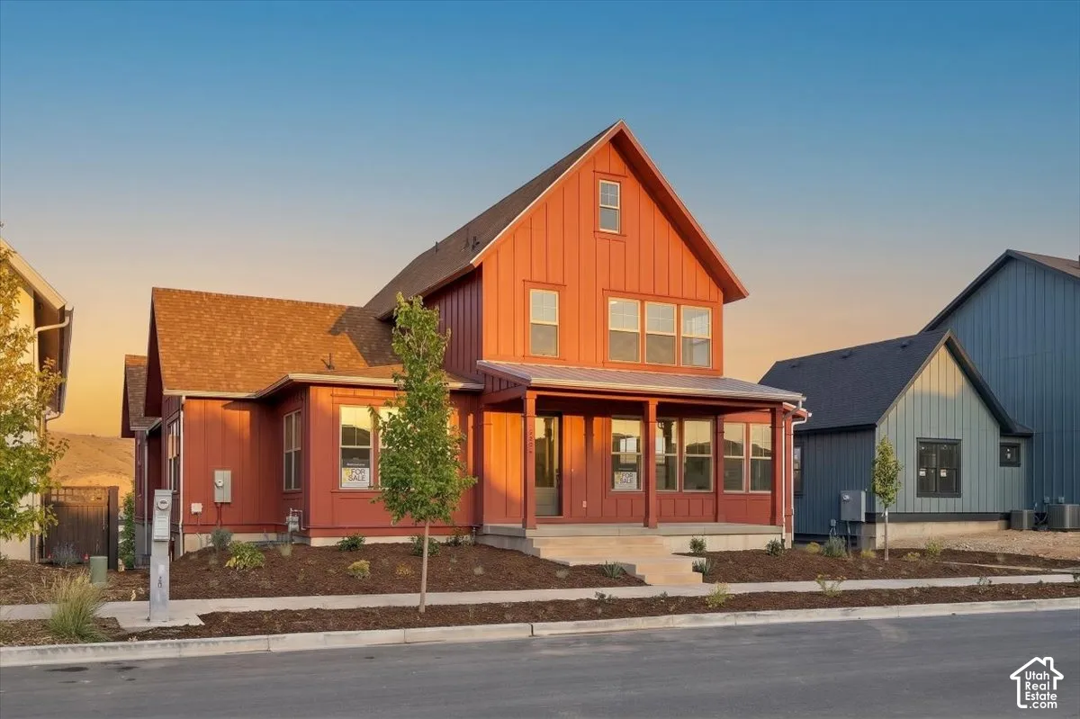 Red board and batten exterior with a covered front porch, asphalt shingle roof, and multiple windows