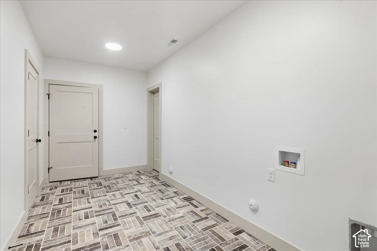 Access to basement from garage. Herringbone-patterned tile flooring, recessed ceiling lighting, and a dedicated laundry hookup