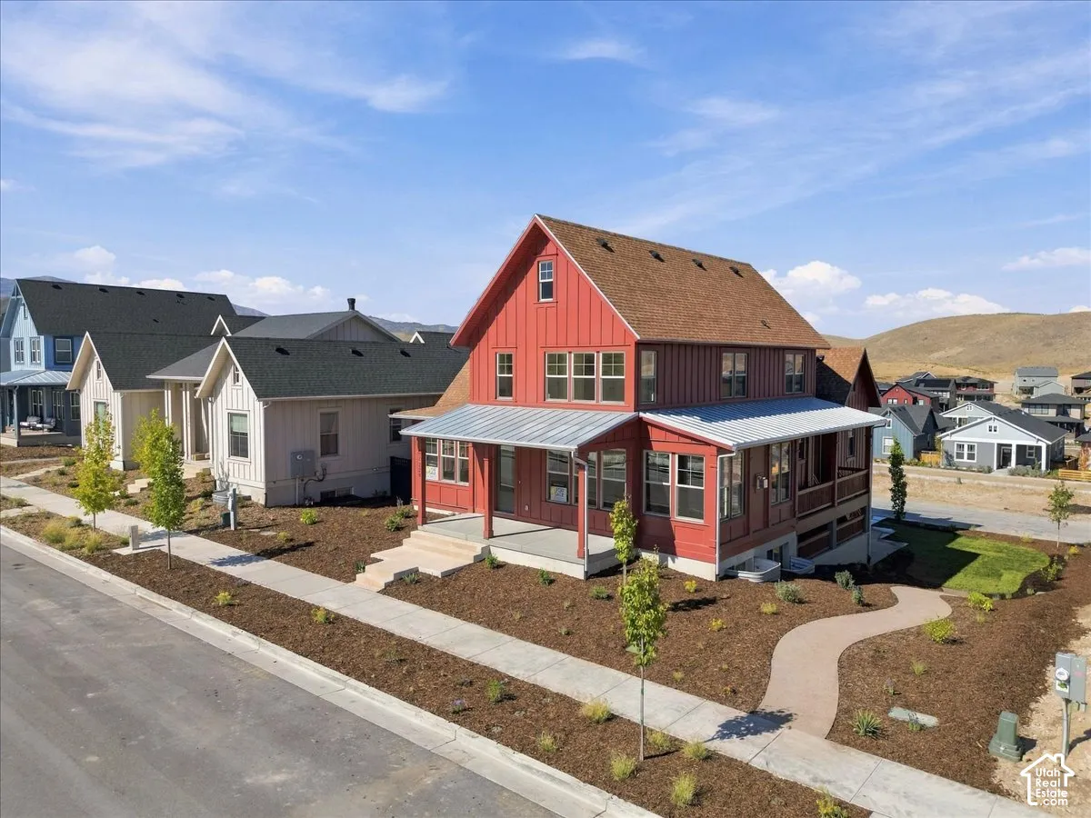 Red vertical siding exterior with a wraparound porch, metal porch roof, and a pitched shingle roof
