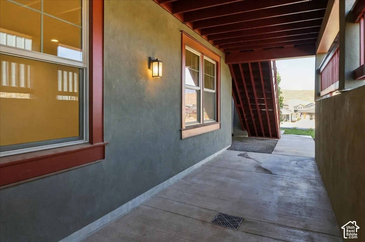 Stucco exterior with contrasting trim, concrete patio, and exterior wall-mounted lighting
