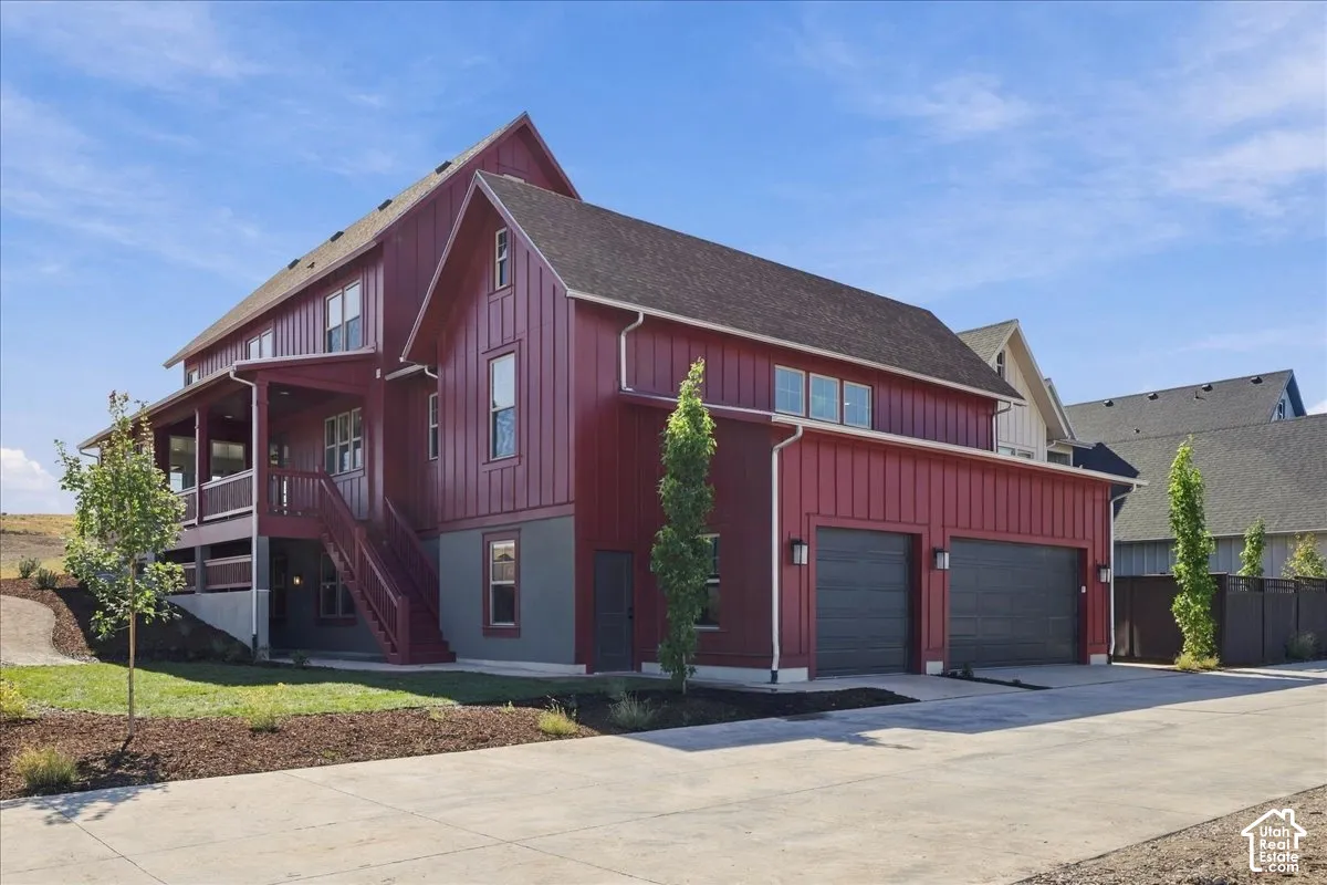 Two-story residence featuring vertical board siding, a covered porch, an exterior staircase, and an attached two-car garage