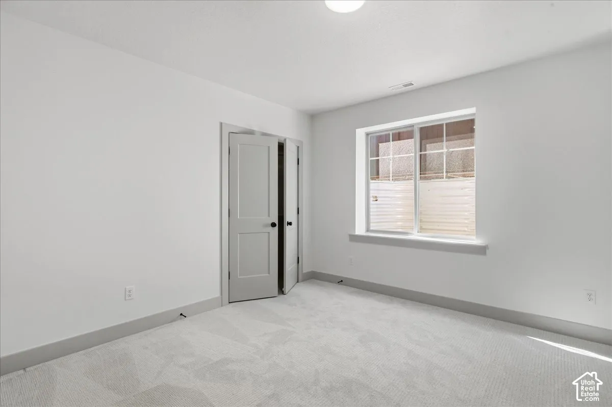 Light gray walls, light patterned carpet, and a window with a white frame