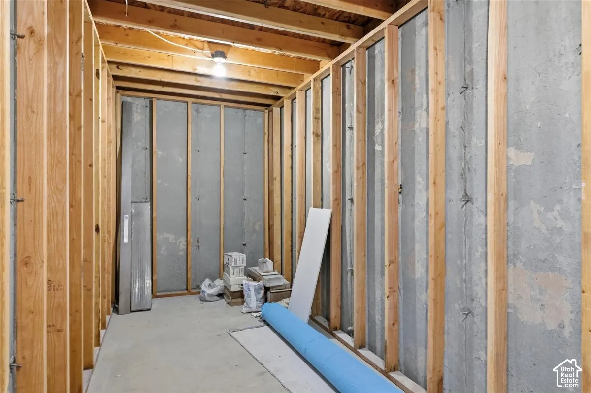 Unfinished interior space featuring exposed wood framing, concrete walls, and concrete flooring