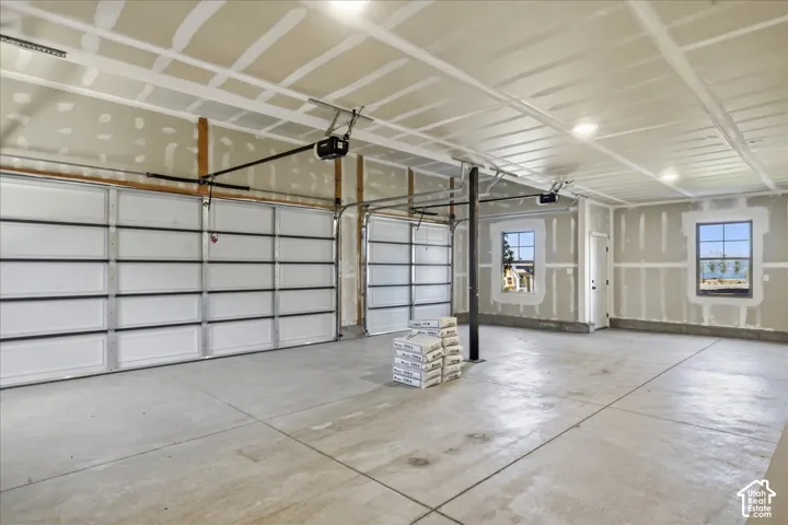 Concrete flooring with two overhead garage doors, two windows, and recessed lighting