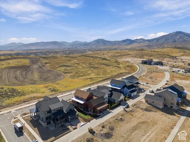 Mountain backdrop, paved roads, organized neighborhood layout, varied architectural styles, and undeveloped land