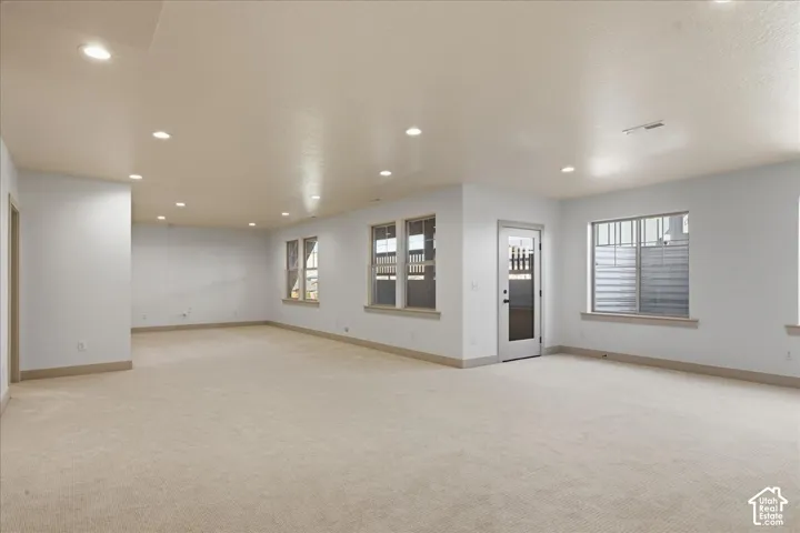 Basemen tExpansive interior space with recessed lighting, light-colored carpeting, multiple windows, and a glass-paneled door
