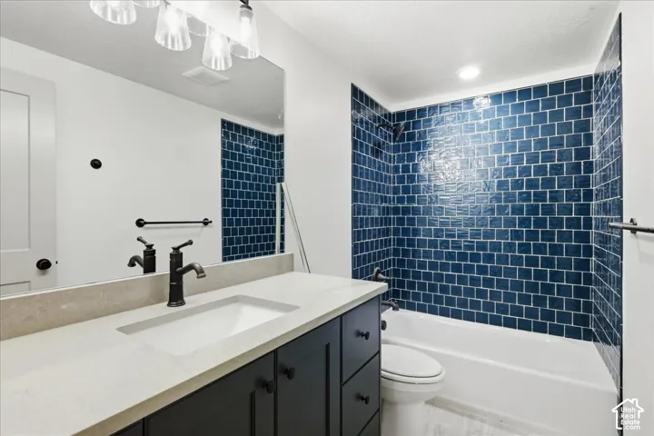 Bathroom featuring a vanity with a light-toned countertop, integrated sink, and dark cabinetry