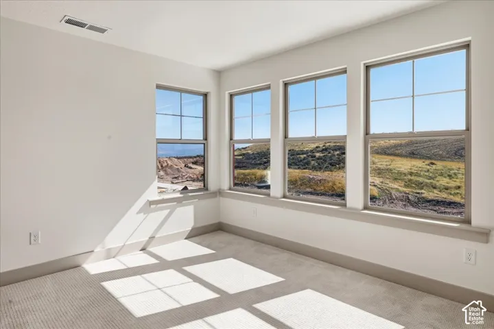 Upstairs guest bedroom 1. Multiple grid-pane windows with trim, light wall color, and carpeted flooring