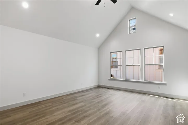 Main Floor Primary Bedroom Vaulted ceiling, wood-finish flooring, recessed lighting, ceiling fan, and multiple windows