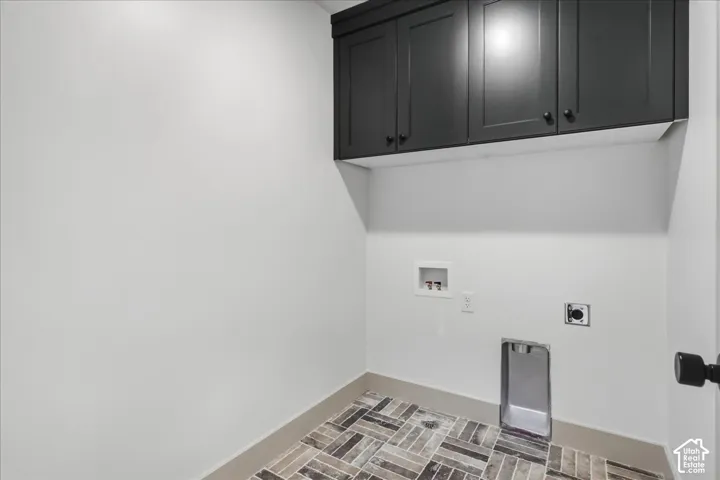 Dark-toned cabinetry, tile flooring with a herringbone pattern, and a utility hookup area