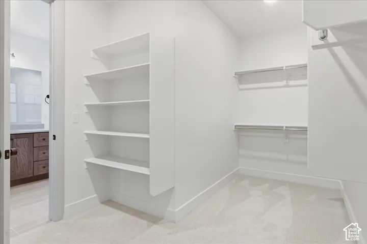 Carpeted closet with built-in shelving, two clothing rods, and white walls