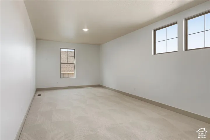 Neutral wall paint, patterned carpet flooring, recessed ceiling lighting, and multiple windows