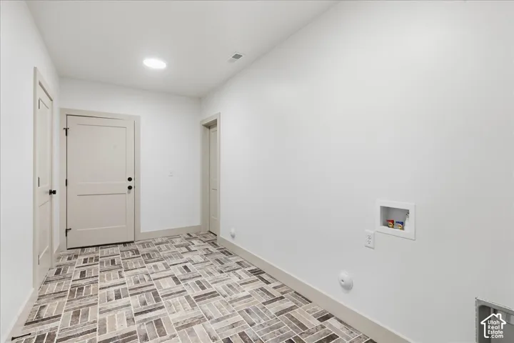 Access to basement from garage. Herringbone-patterned tile flooring, recessed ceiling lighting, and a dedicated laundry hookup