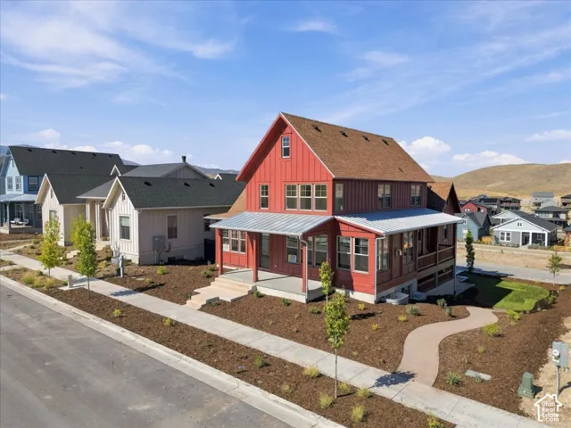 Red vertical siding exterior with a wraparound porch, metal porch roof, and a pitched shingle roof