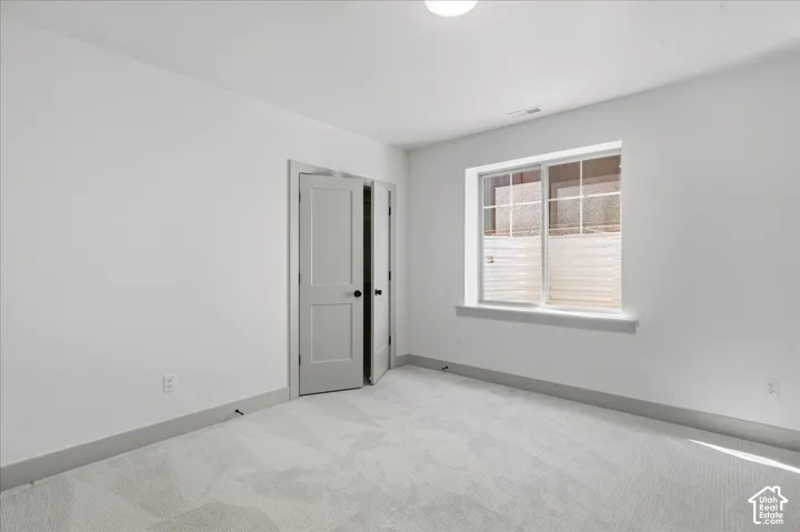 Light gray walls, light patterned carpet, and a window with a white frame