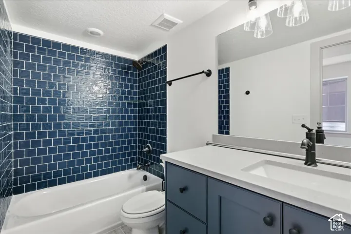 Subway tile shower surround, integrated single-basin vanity sink, dark bronze fixtures, dark blue vanity cabinetry, and a framed mirror