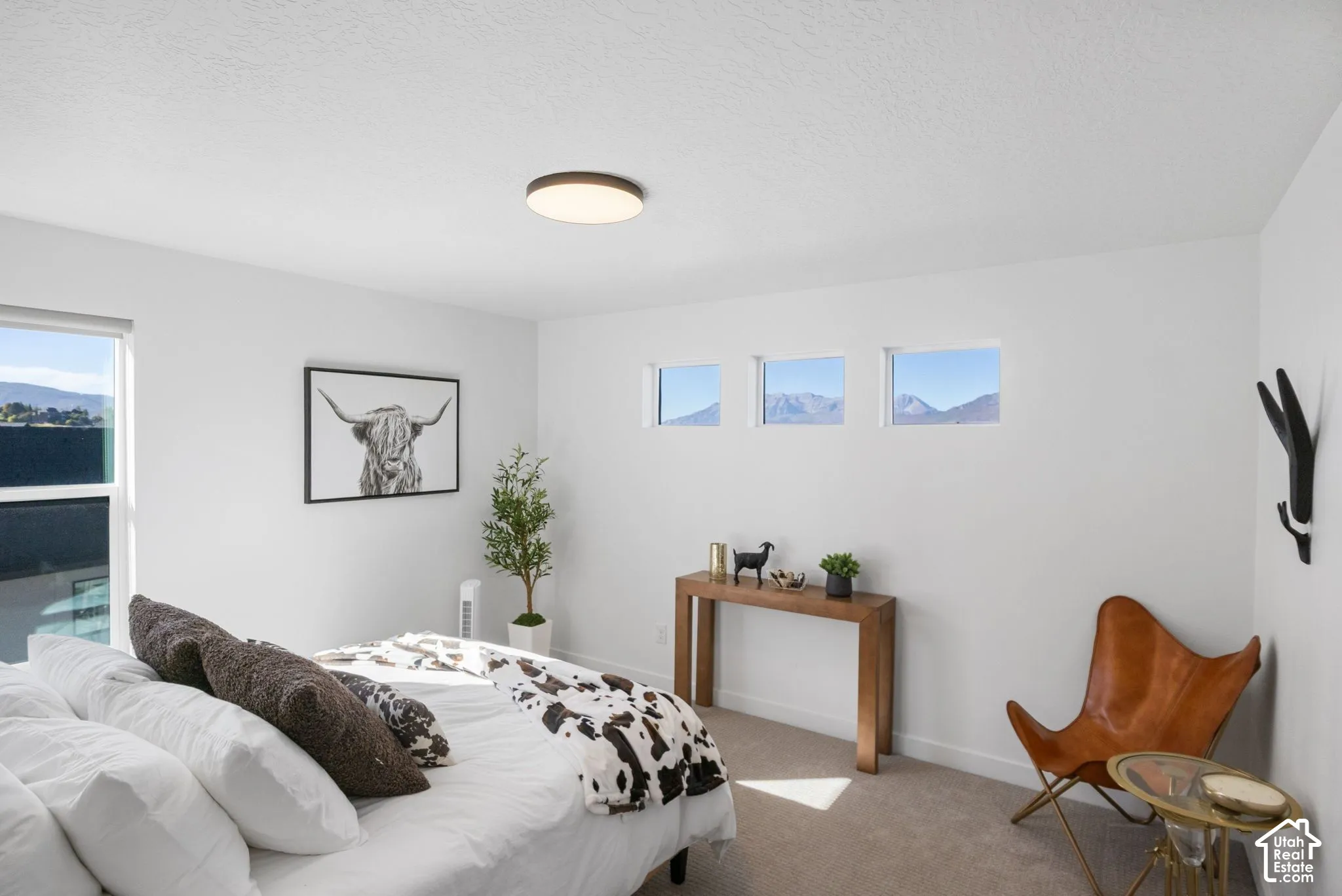 Bright room with white walls, a large window, three smaller square windows, and a flush-mount ceiling light
