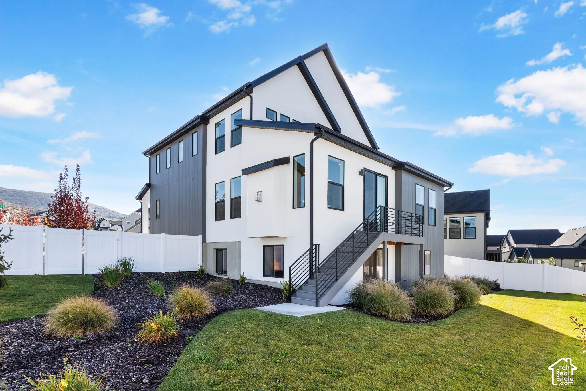 Modern two-tone exterior with white siding and dark accents, featuring a multi-level design