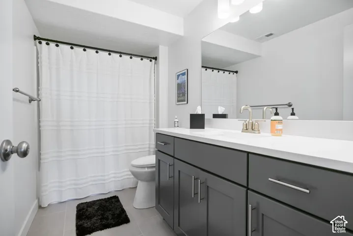 Vanity with a white countertop and dark gray cabinetry, brushed nickel faucet, large wall-mounted mirror, and overhead vanity lighting