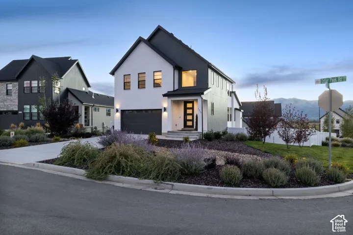 Contemporary exterior with white siding and dark accents, featuring a two-car garage and a modern entry door