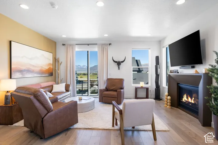 Recessed lighting illuminates the open living space, featuring wood-finish flooring and a built-in fireplace