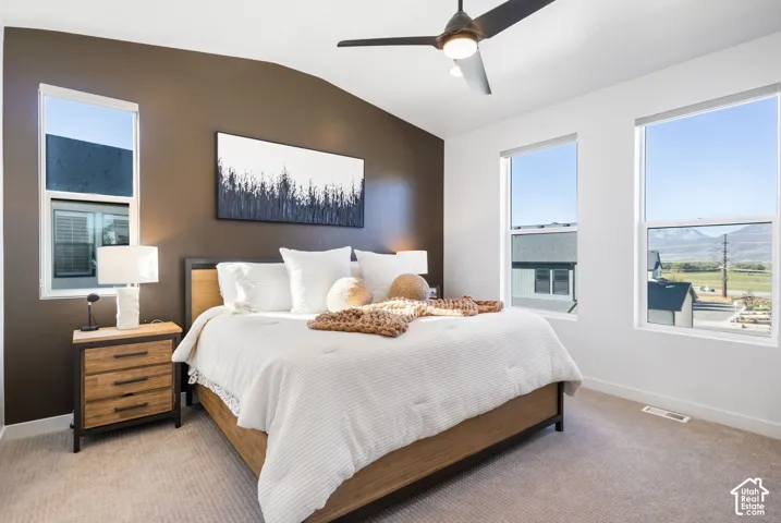 Vaulted ceiling with a ceiling fan, wall-to-wall carpeting, and multiple windows