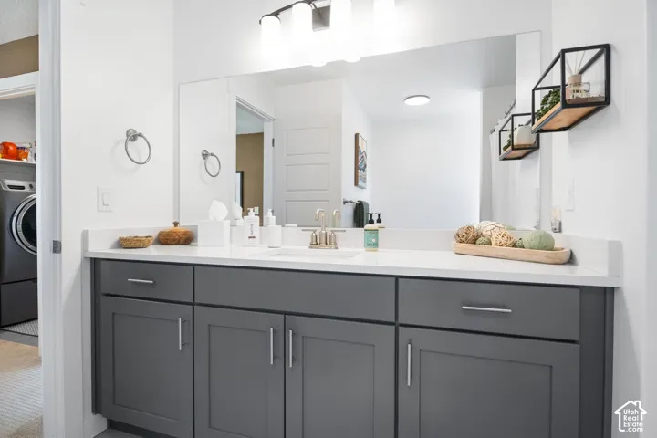 Gray cabinetry with brushed nickel hardware, expansive vanity mirror, and white countertop